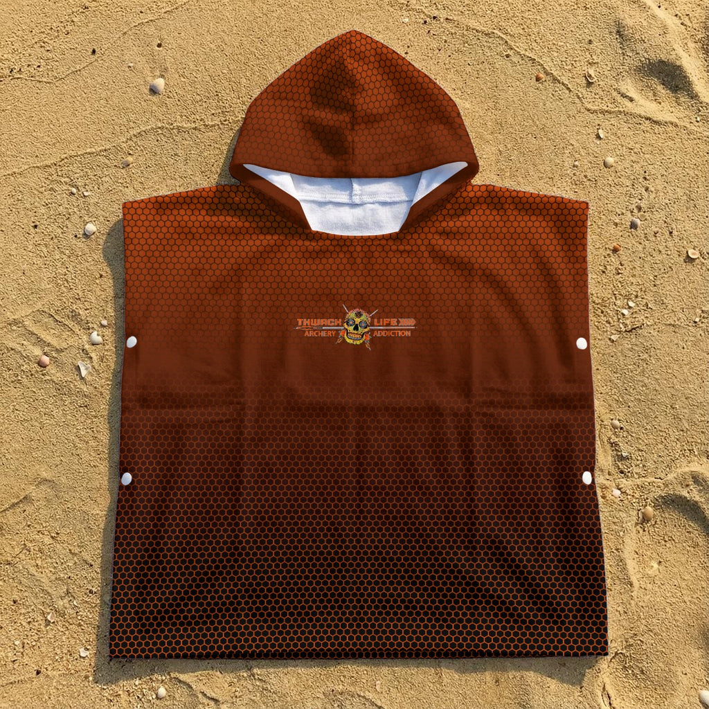 TLAA Sugar Skull Kids' Towel Poncho laid flat on sand, showing the orange hex fade, hood and side snaps