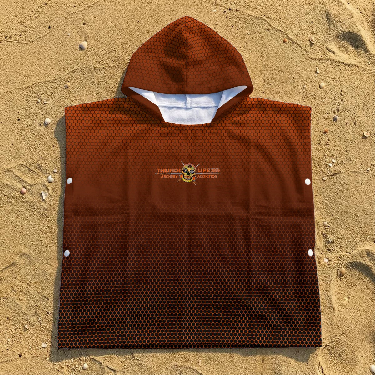 TLAA Sugar Skull Kids' Towel Poncho laid flat on sand, showing the orange hex fade, hood and side snaps