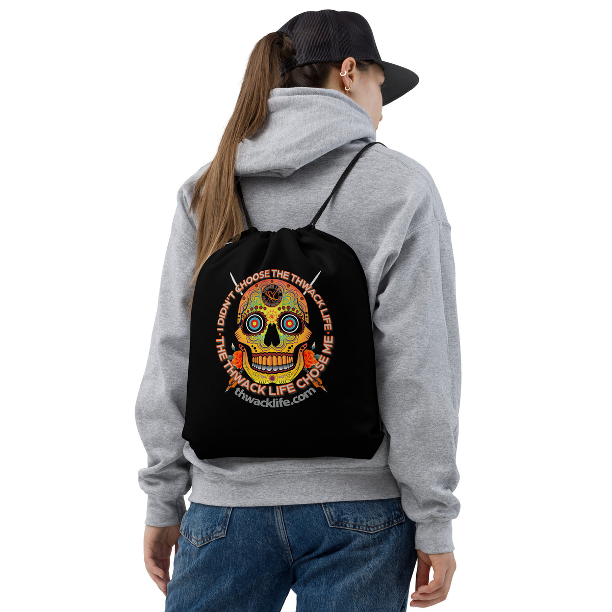 Sugar Skull Drawstring Bag, worn on the back of a model in a gray hoodie, showing the Sugar Skull inside the "I didn't choose the Thwack Life, the Thwack Life chose me" ring