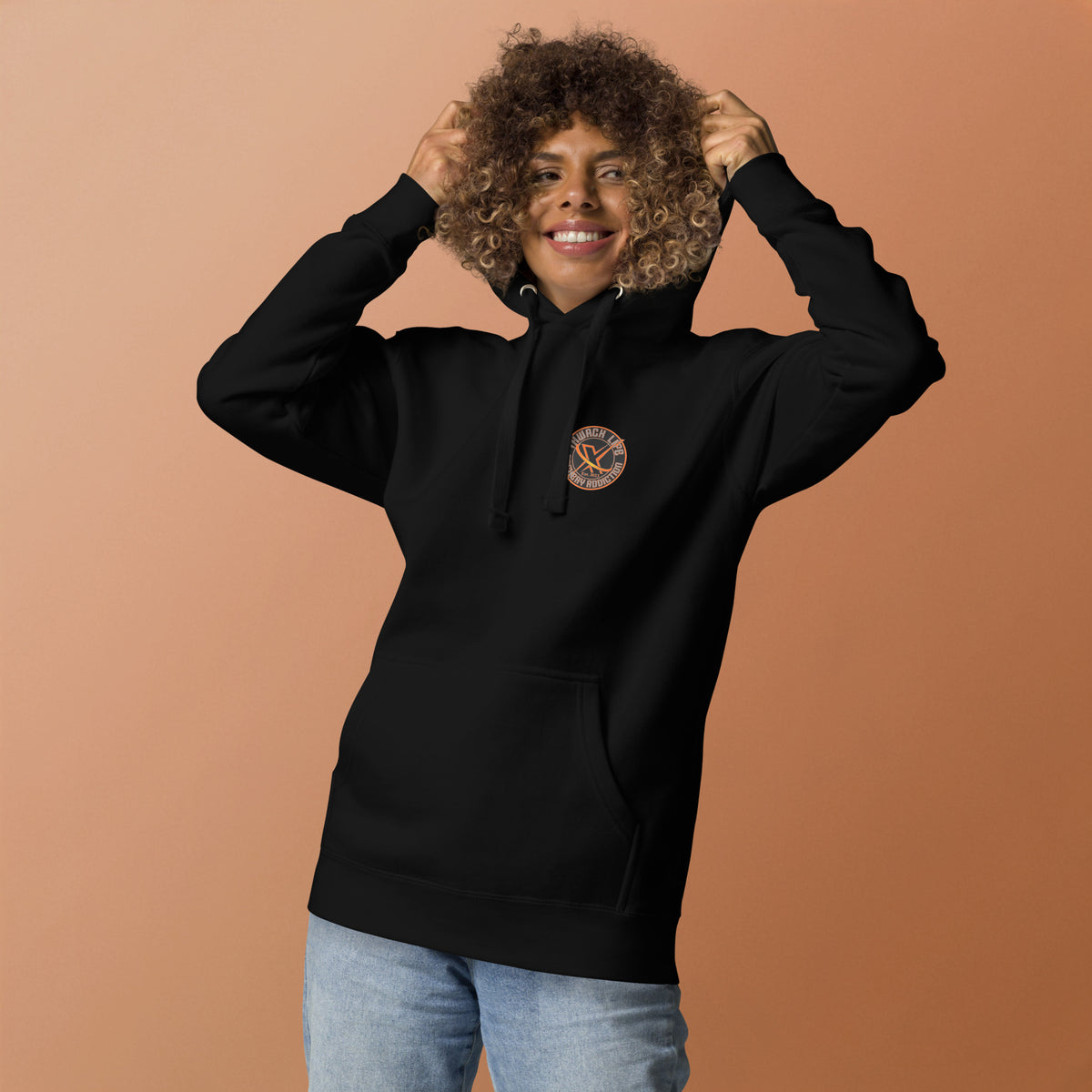 Sugar Skull Pullover Hoodie in Black, front view on a model holding the hood, orange backdrop