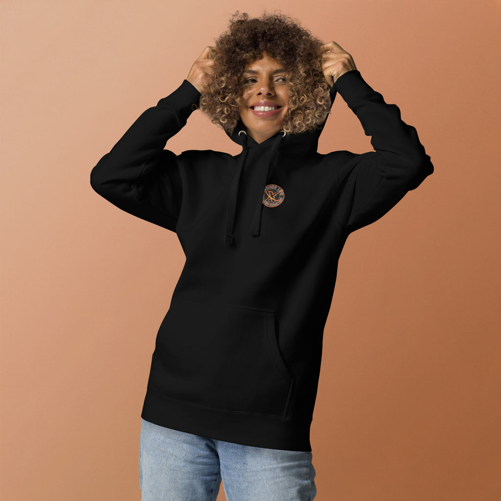Thwack It Pullover Hoodie in Black, front view on a model holding the hood, orange backdrop